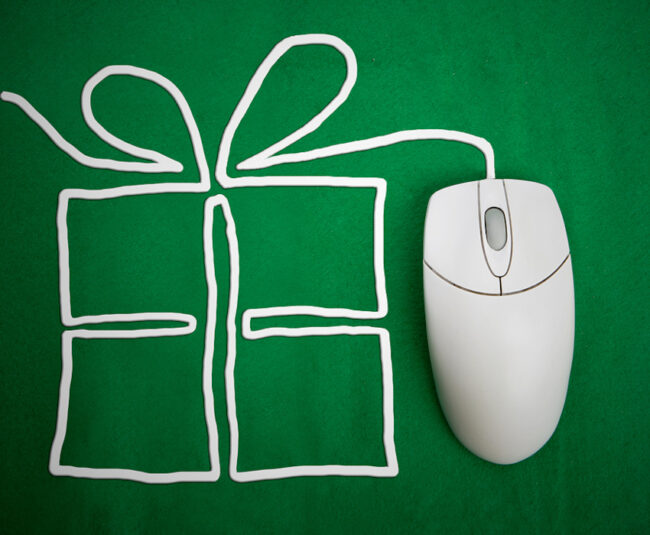 a wired mouse sits on a green surface; its wire is arranged to look like a present