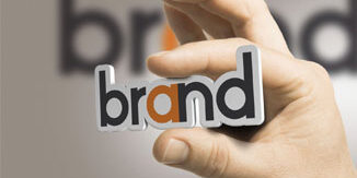 A hand holding the word "brand" between the index finger and thumb