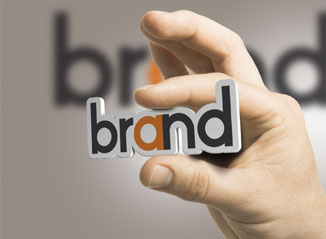 A hand holding the word "brand" between the index finger and thumb