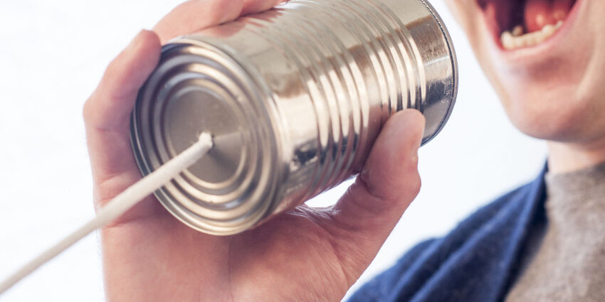 Man speaks into a empty tin can with a string coming out of the bottom