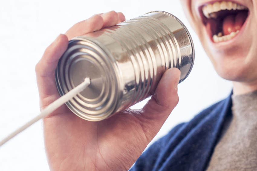 Man speaks into a empty tin can with a string coming out of the bottom