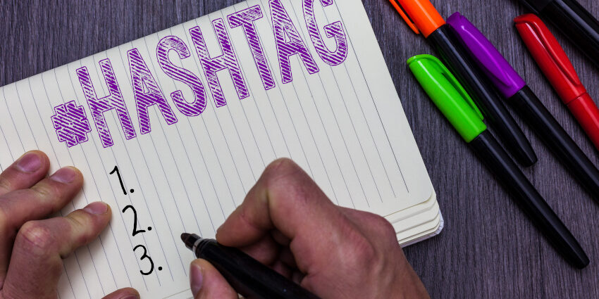 Person writing on a piece of lined paper with a marker, text: "#hashtag" and lists 1, 2, 3