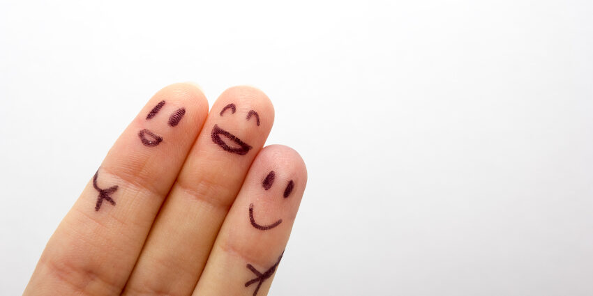 Close up on three fingers with faces drawn on them and clustered together