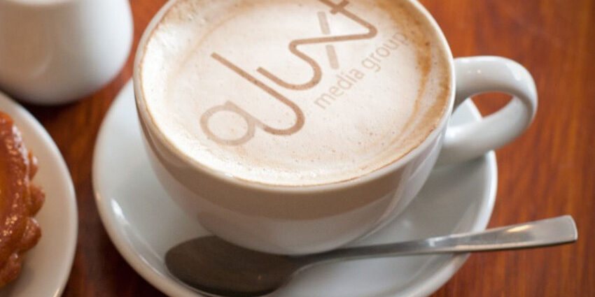 aJuxt Media Group logo in coffee foam