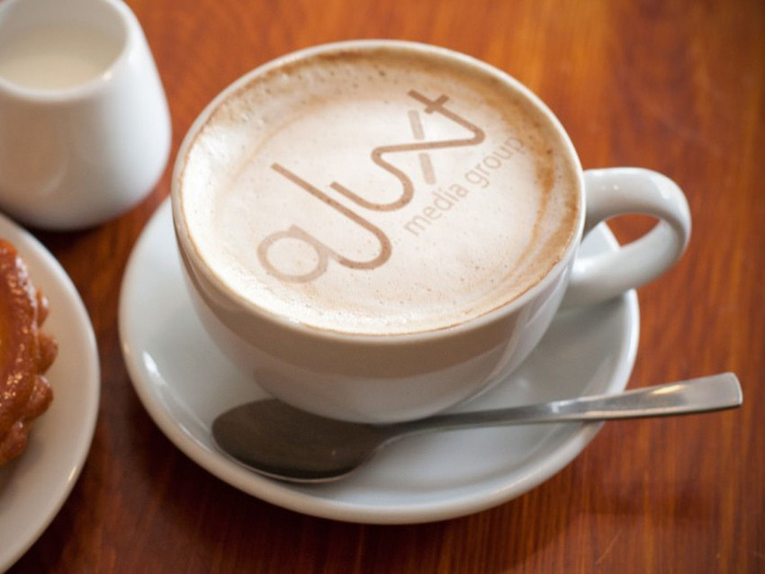 aJuxt Media Group logo in coffee foam