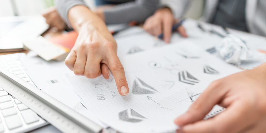 Business people looking through business logo sketches by a graphic designer