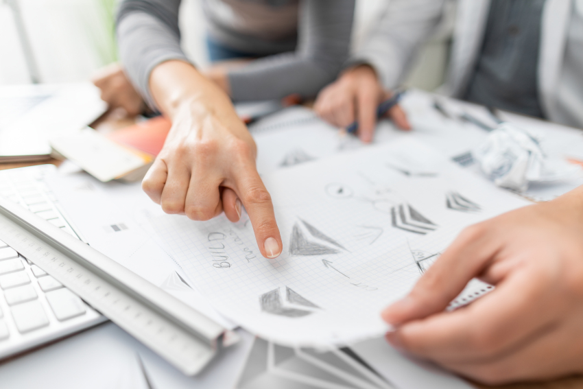 Business people looking through business logo sketches by a graphic designer
