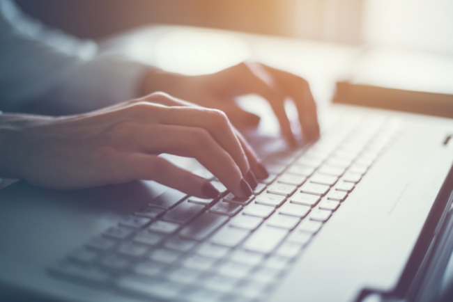 A woman types on a laptop