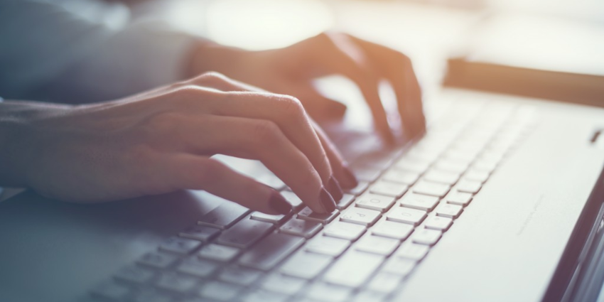 A woman types on a laptop