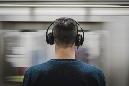 view from the back of a man wearing headphones while waiting to commute