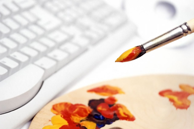 paintbrush and paint palette sitting next to a keyboard; representing digital design inspiration