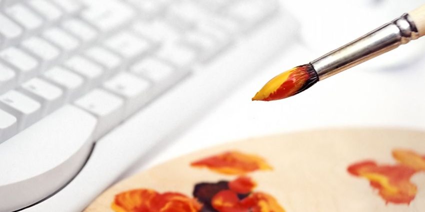 paintbrush and paint palette sitting next to a keyboard; representing digital design inspiration