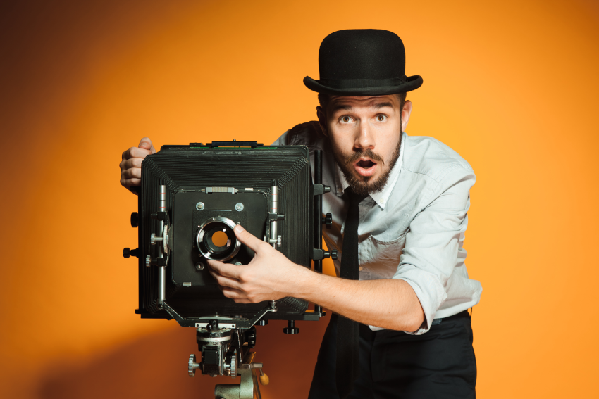 photography marketing tips featured image; man in bowler hat using an old-fashioned camera with surprised expression