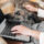 Woman working on laptop while petting large dog's head, dog is resting chin on laptop keyboard