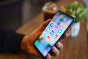 Person using a smart phone with social media icons showing on the screen