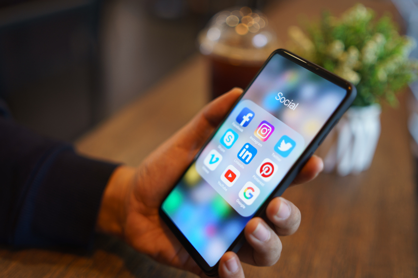 Person using a smart phone with social media icons showing on the screen