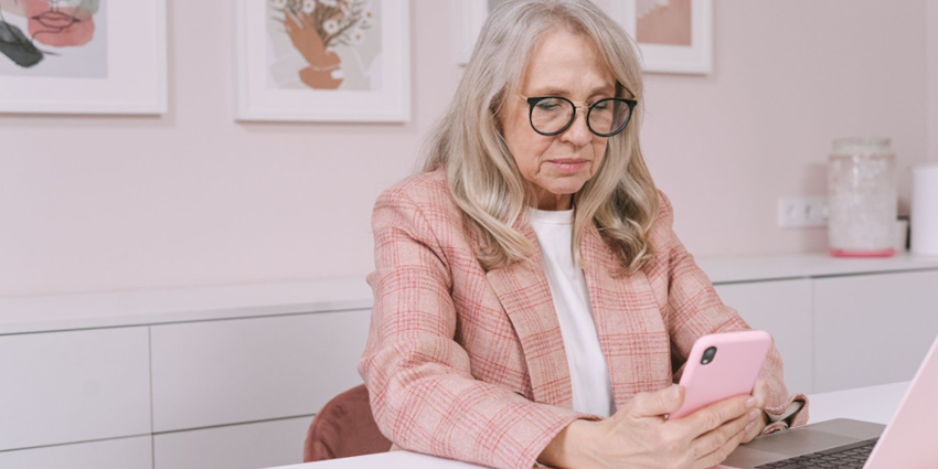 A middle-aged woman is looking at her phone and reading from it intently