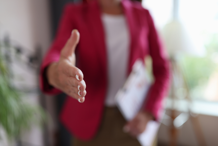 Closeup of woman hand reaching out for greeting in office. Female handshake friendliness at business meeting