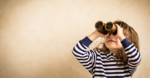 a little girl holds binoculars up to her eyes and looks up