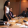 woman speaks in a boardroom meeting with other professionals at a meeting table