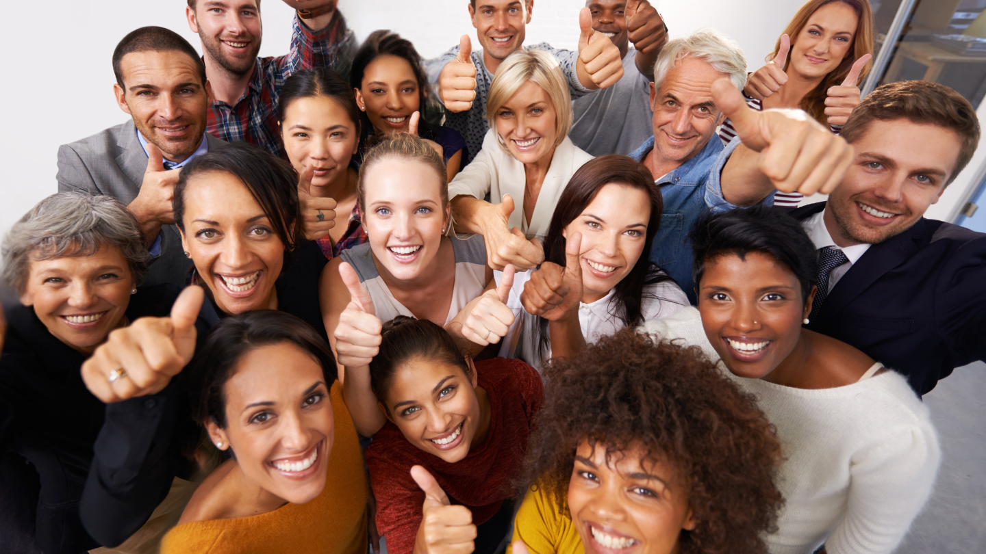 Group of diverse people smiling and giving thumbs-up, showing unity and positivity.